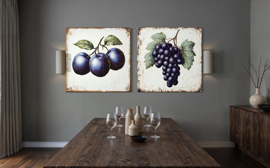 Set of two rustic botanical canvas prints featuring plums and grapes in a dining room setting.