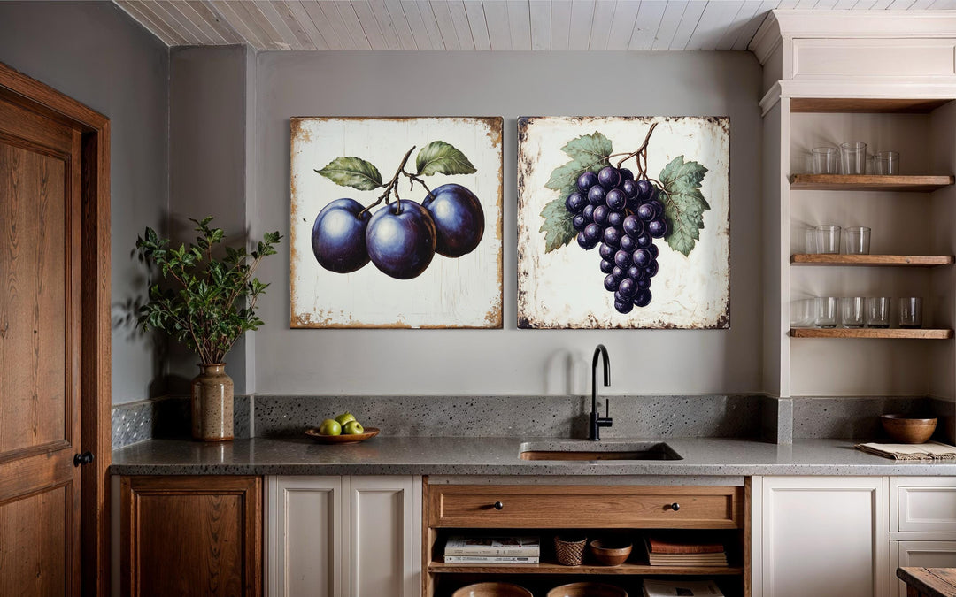 Set of two rustic botanical canvas prints featuring vintage-style plums and grapes in a kitchen.