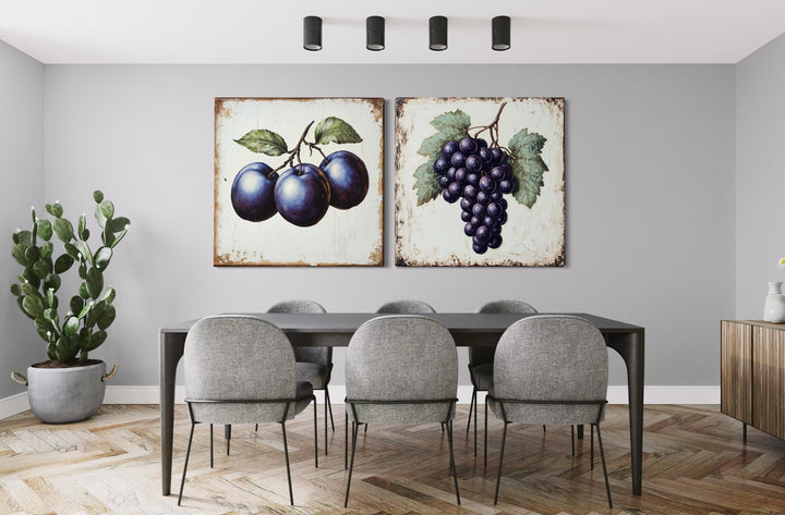 Two vintage botanical canvas prints of plums and grapes hanging in a modern dining room.