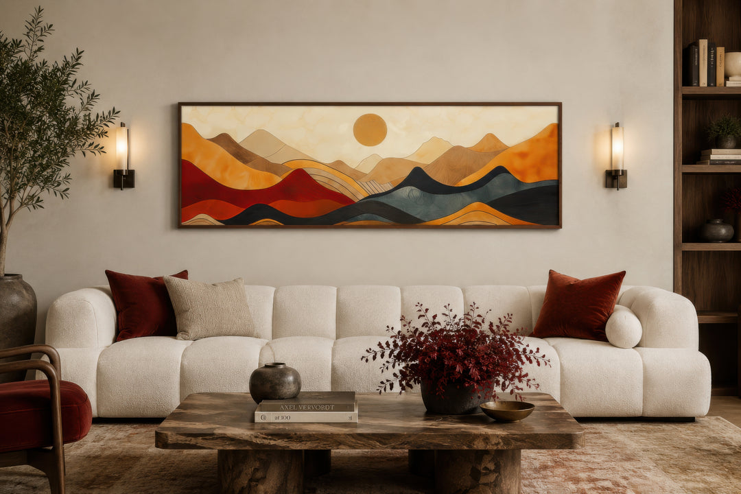 Mid-century modern horizontal canvas art of stylized mountains in earthy tones above a white sofa.