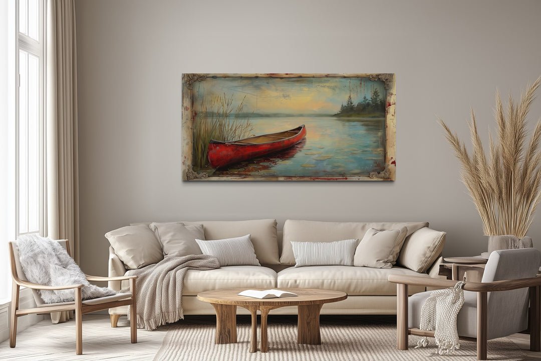 Vintage red canoe lake painting in a rustic frame above a neutral sofa in a cabin-style living room.