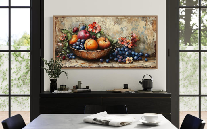Vintage still life fruit bowl framed canvas wall art above a black sideboard in a dining room.