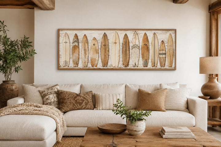 Vintage surfboard wall art in a wooden frame hanging above a neutral sofa in a coastal living room.