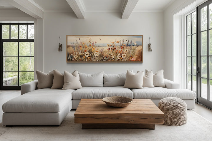 Vintage wildflowers field canvas wall art in a long horizontal frame above a modern sectional sofa.