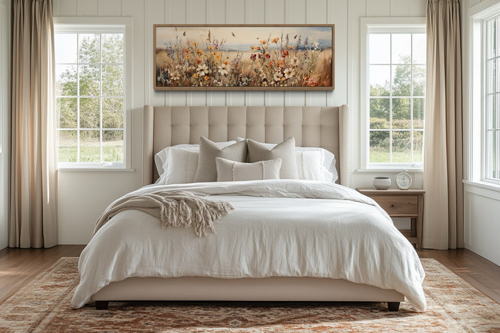 Vintage wildflowers field canvas wall art in a long horizontal frame hanging above a bed.
