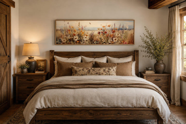 Vintage wildflowers field canvas wall art in a long horizontal frame hanging above a wooden bed.