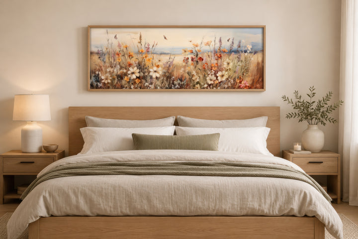 Vintage wildflowers field canvas wall art in a wooden frame hanging above a bed.