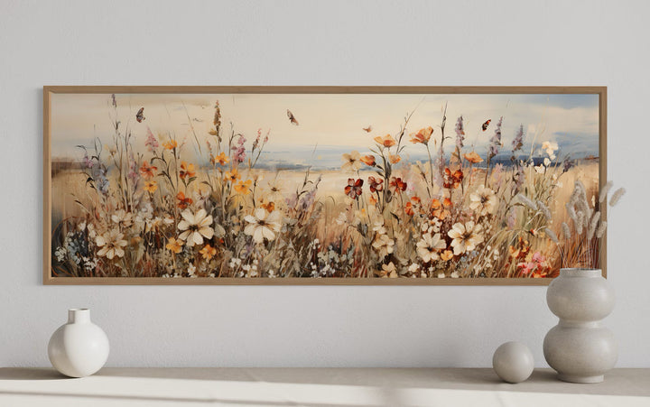 Vintage wildflowers field canvas wall art in a wooden frame above a minimalist console table.