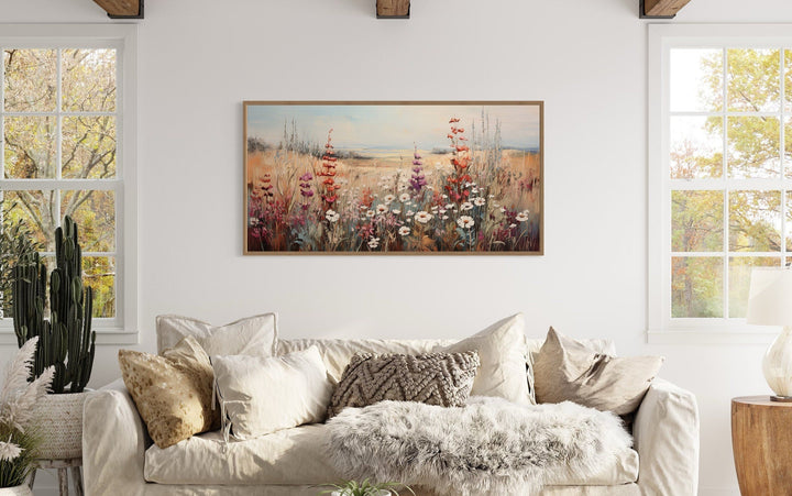Vintage wildflowers field painting in a horizontal frame above a white sofa in a farmhouse room.