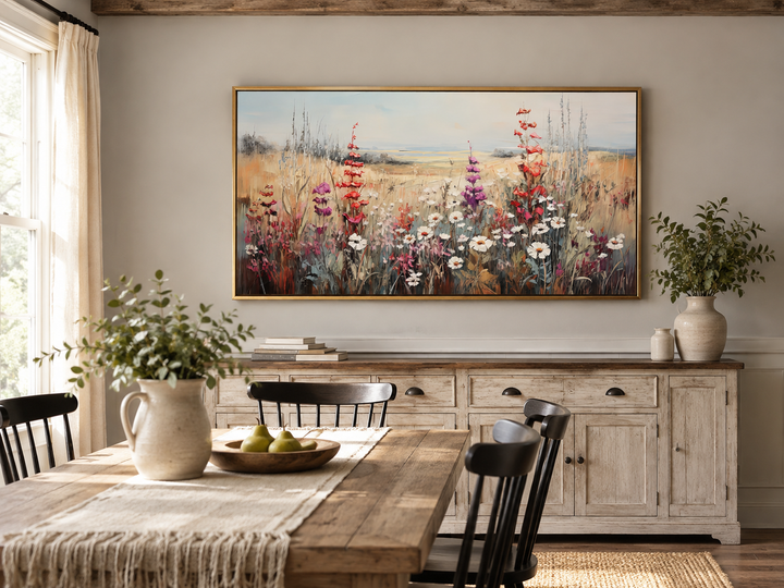 Vintage wildflowers field canvas wall art in a gold frame above a rustic sideboard in a dining room.