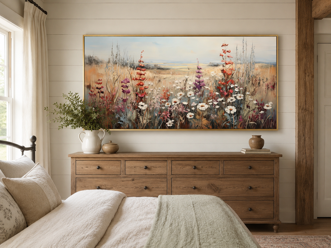 Vintage wildflowers field canvas wall art in a gold frame above a wooden dresser in a bedroom.