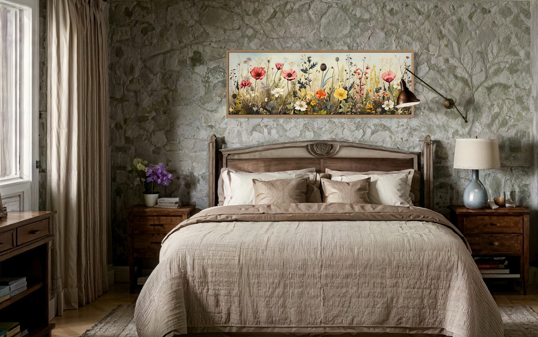 Vintage wildflowers field horizontal framed canvas wall art hanging above a bed in a rustic room.