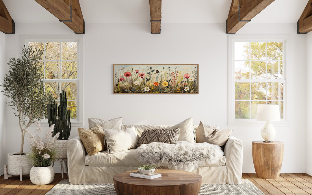 Vintage wildflowers field long horizontal framed canvas wall art above a sofa in a rustic room.