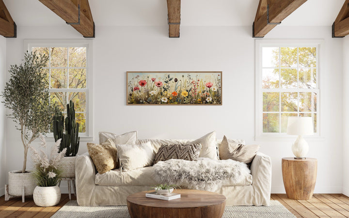 Vintage wildflowers field long horizontal framed canvas wall art above a sofa in a rustic room.