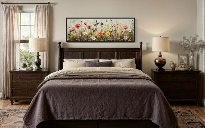 Vintage wildflowers field long horizontal framed canvas wall art hanging above a dark wood bed.
