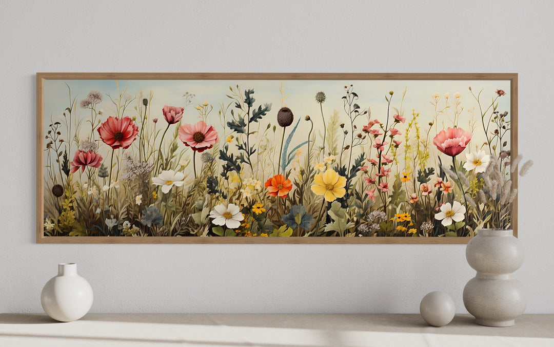 Vintage wildflower field horizontal framed canvas wall art above a console with ceramic vases.