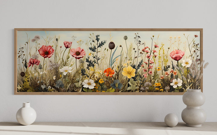 Vintage wildflower field horizontal framed canvas wall art above a console with ceramic vases.