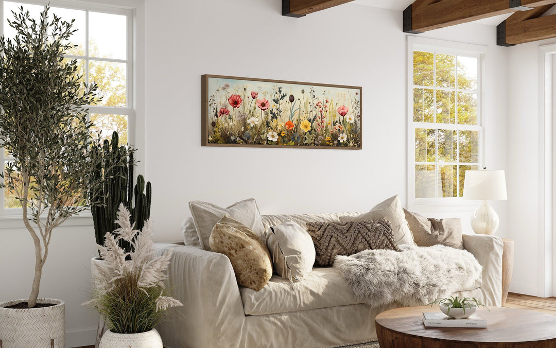 Vintage wildflowers field long horizontal framed canvas wall art hanging above a sofa in a room.