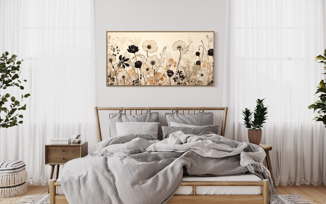 Vintage wildflowers wall art with neutral floral silhouettes on canvas above a wooden bed frame.