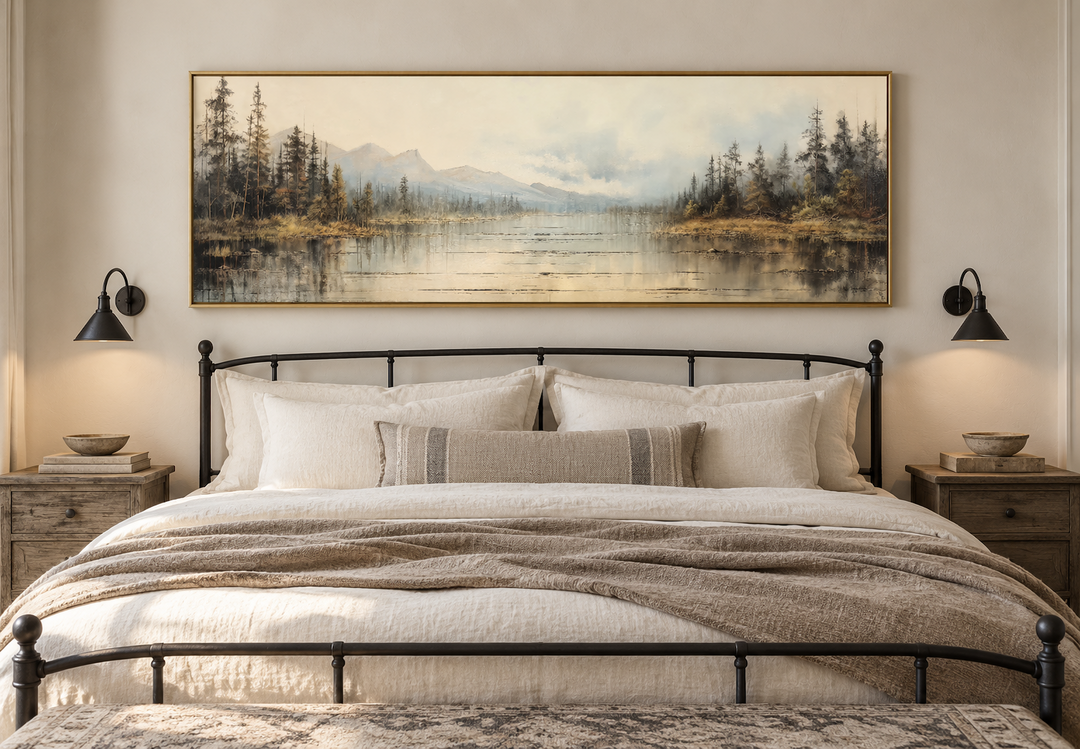 Vintage neutral lake landscape long horizontal wall art in a gold frame above a black iron bed.