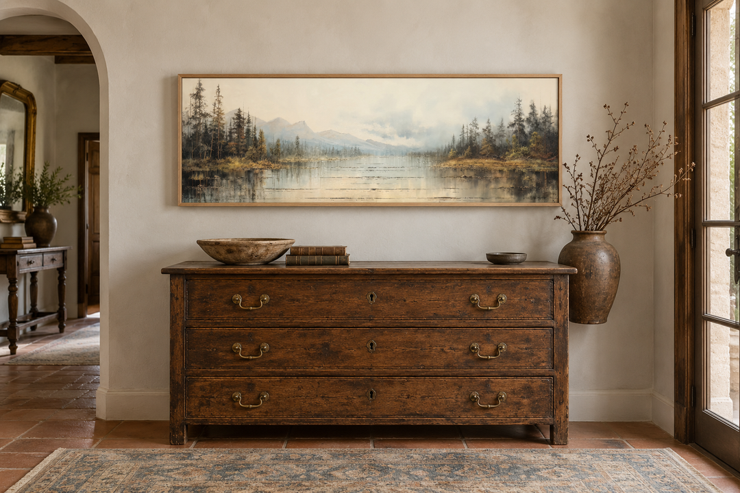 Vintage neutral lake landscape horizontal wall art in a thin wood frame above a rustic dresser.