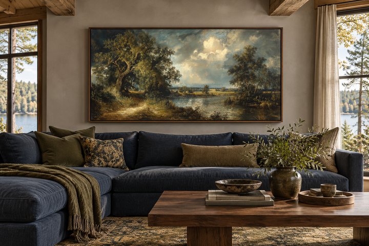 Vintage lake landscape framed canvas wall art hanging above a navy blue sectional sofa.
