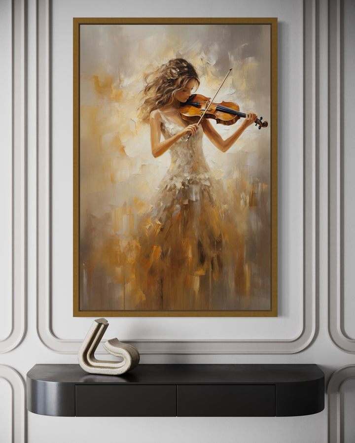 Framed canvas wall art of a woman in a gold dress playing the violin above a black console table.