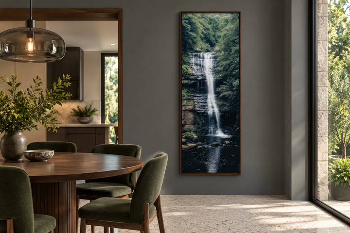Tall narrow vertical framed canvas wall art featuring a serene waterfall in a lush green forest.