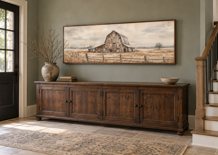 Rustic barn wall art in a long horizontal frame above a dark wood sideboard in a farmhouse entryway.