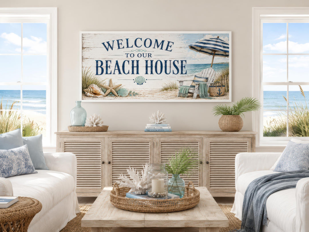 Welcome To Our Beach House rustic canvas sign above a wooden sideboard in a coastal living room.