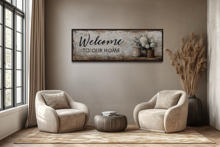 Welcome to Our Home long horizontal farmhouse wall art with flowers above two chairs in a room.