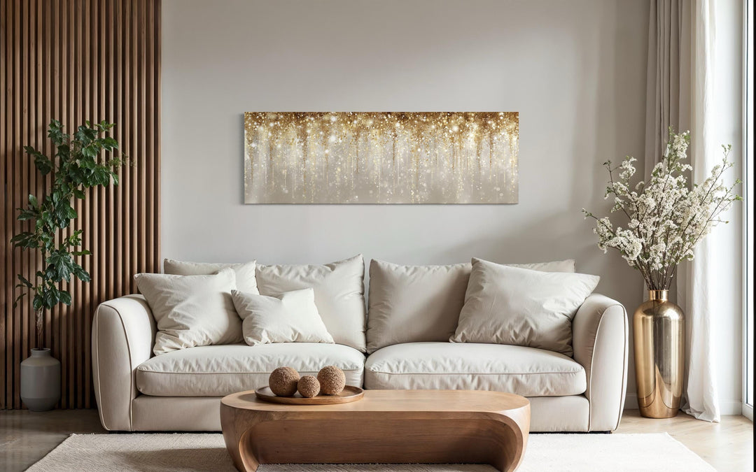 White and gold abstract rain horizontal canvas wall art displayed above a modern beige sofa.