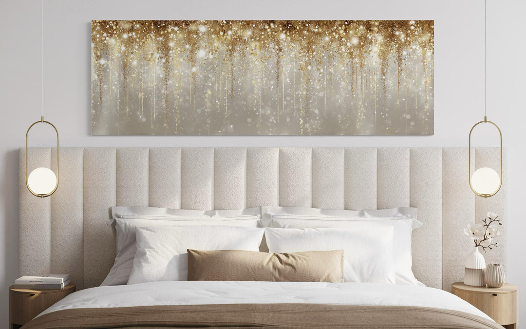 Long horizontal canvas wall art featuring abstract gold rain over a neutral bed and headboard.