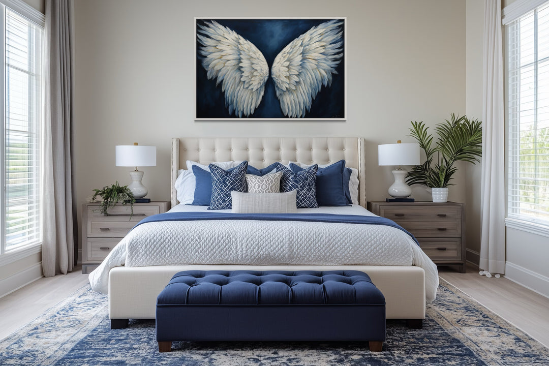 White angel wings on blue background framed canvas wall art hanging above a bed in a bedroom.
