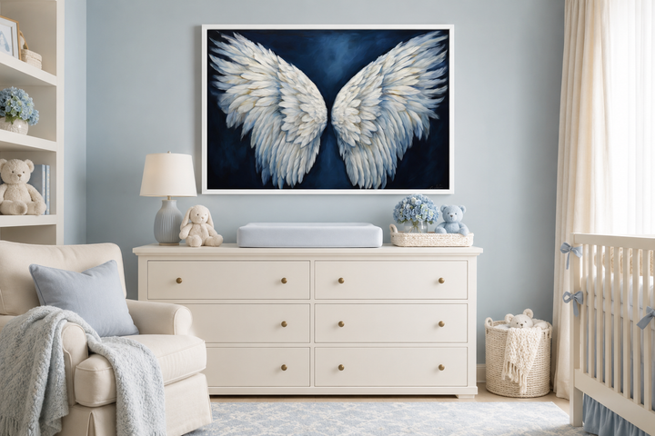 White angel wings on a dark blue background framed canvas wall art hanging in a nursery.