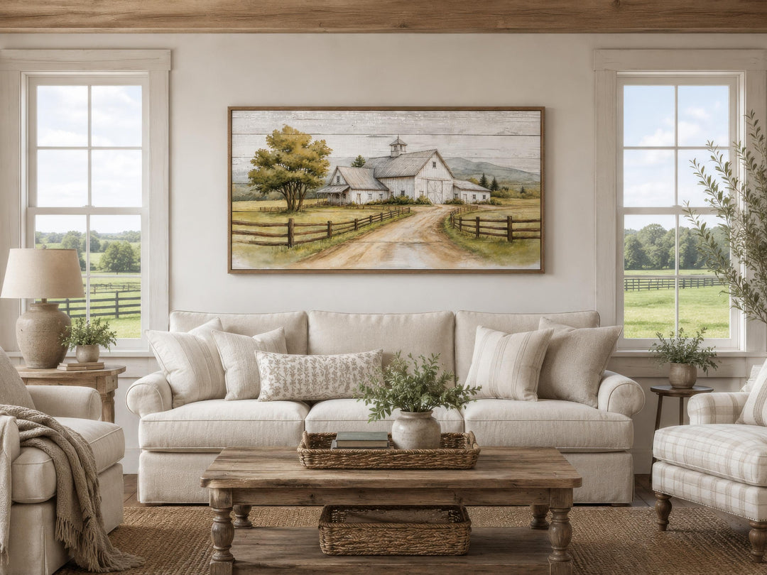 Rustic white barn landscape wall art hanging above a sofa in a farmhouse living room.