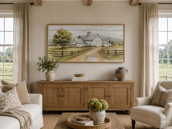 Rustic white barn canvas wall art hanging above a wooden sideboard in a farmhouse living room.
