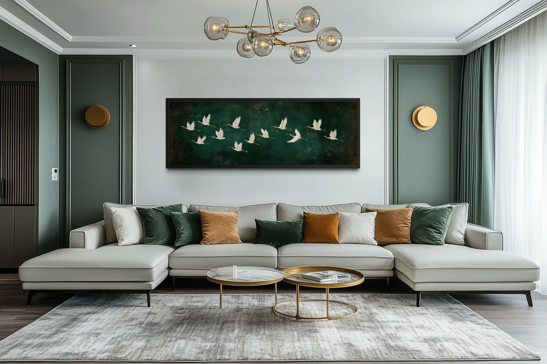 White birds flying across a long horizontal emerald green canvas wall art above a modern sofa.