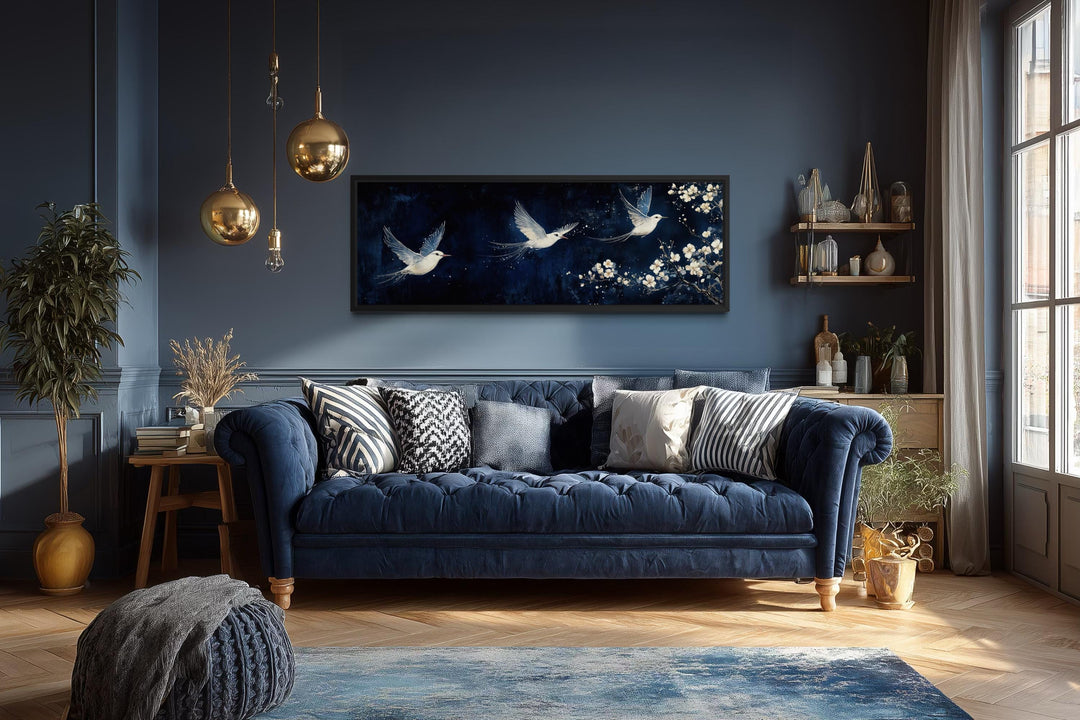 White birds on navy background long narrow wall art above a blue sofa in a modern living room.
