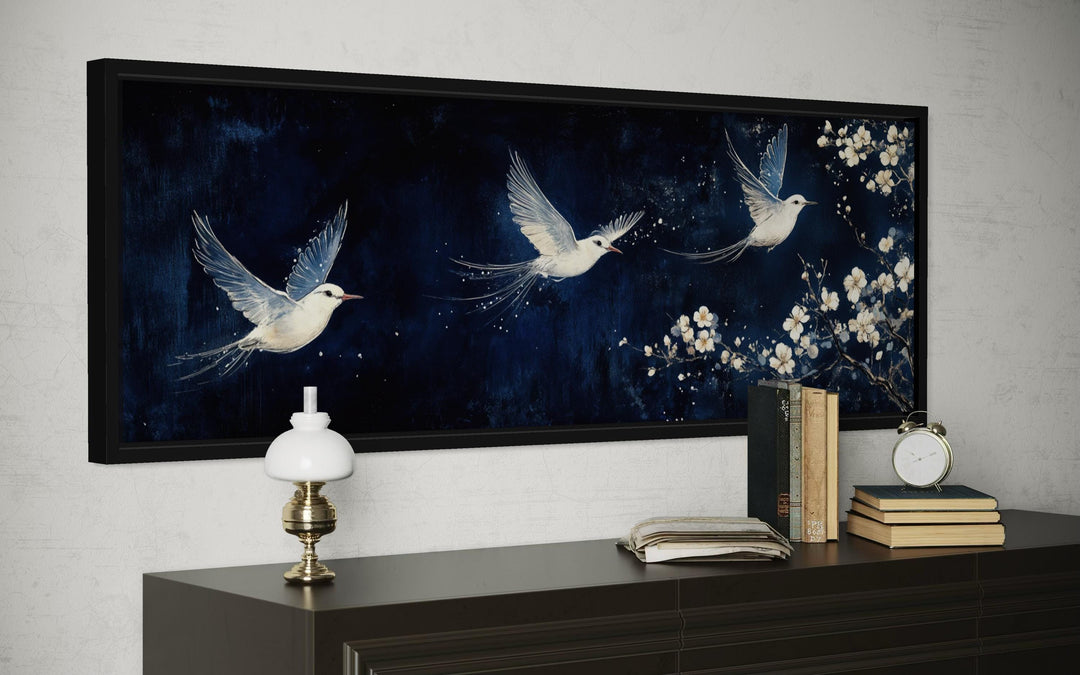 Long narrow canvas print of three white birds flying against a navy blue floral background.