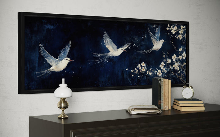 Long narrow canvas print of three white birds flying against a navy blue floral background.