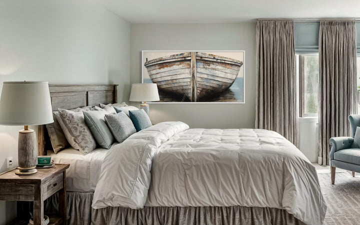 A framed canvas wall art featuring a rustic old boat hangs above a bed in a coastal-style bedroom.