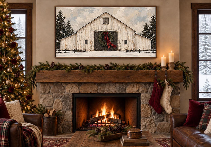 Framed canvas wall art of a white barn with a Christmas wreath above a rustic stone fireplace.