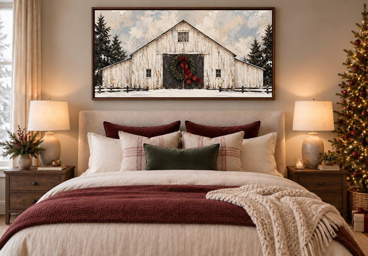 White Christmas Barn framed canvas wall art with evergreen wreath and burgundy bow above a bed.