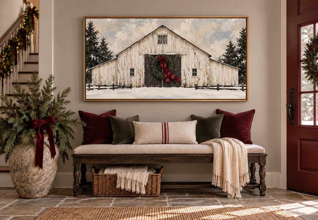 White Christmas Barn framed canvas wall art with evergreen wreath and burgundy bow above a bench.