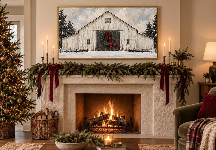 Framed canvas art of a white barn with a Christmas wreath above a decorated fireplace mantel.