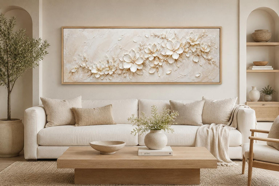 Long horizontal white floral canvas wall art above a cream sofa in a neutral living room.