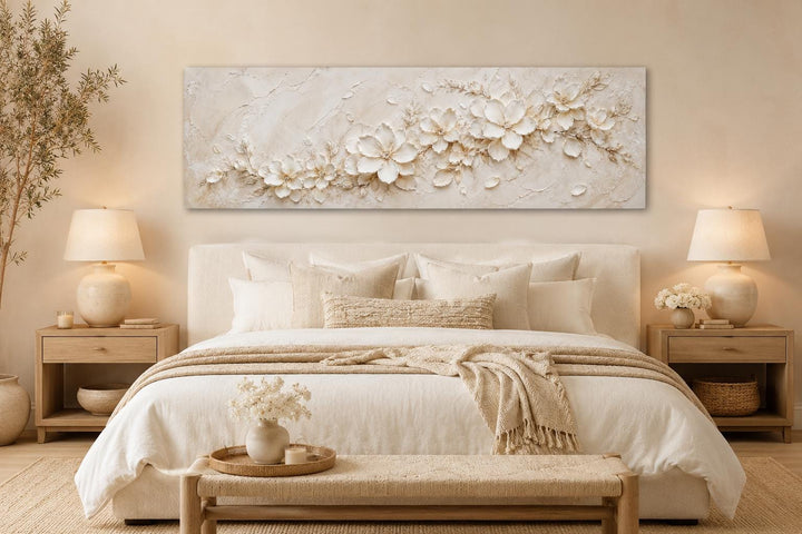 Long horizontal canvas with textured white floral art above a neutral-toned bed.