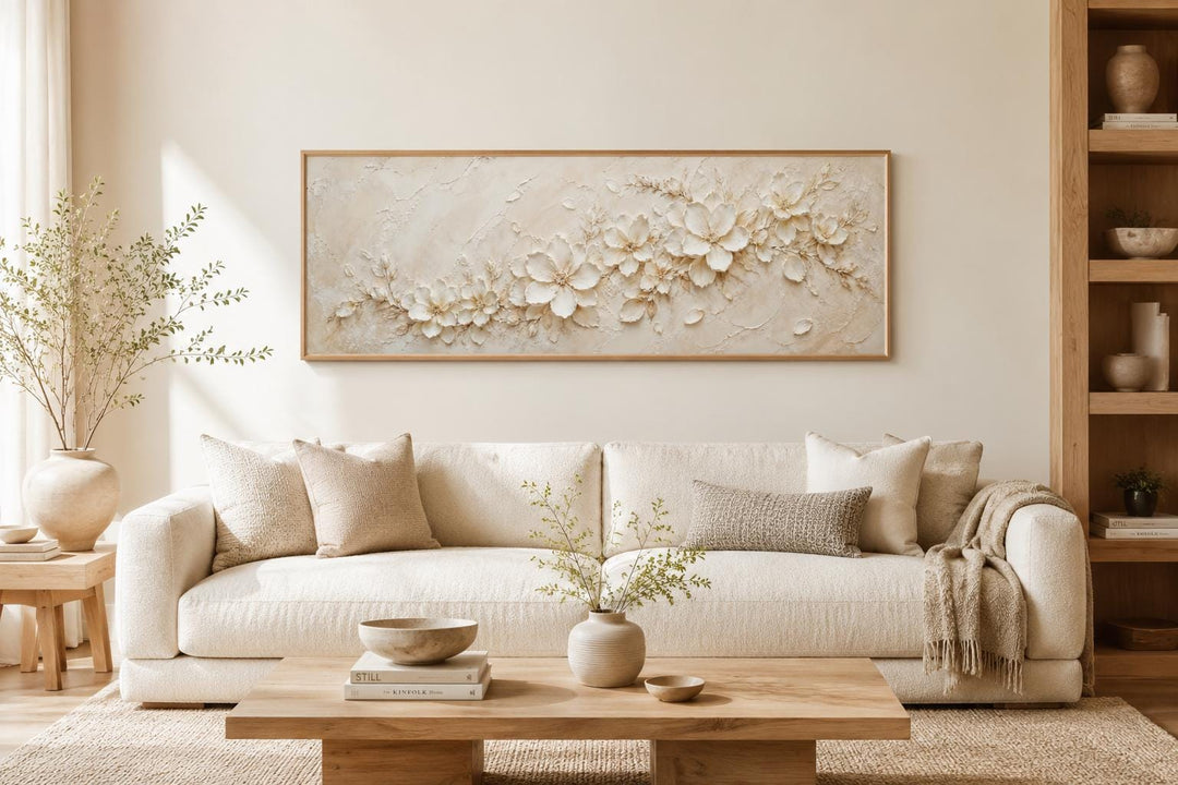 Long horizontal canvas with textured white floral art above a neutral sofa in a minimalist room.
