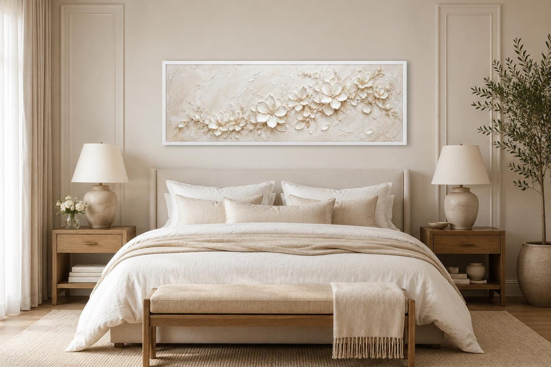 Long horizontal white floral canvas art above a bed in a neutral, minimalist bedroom.